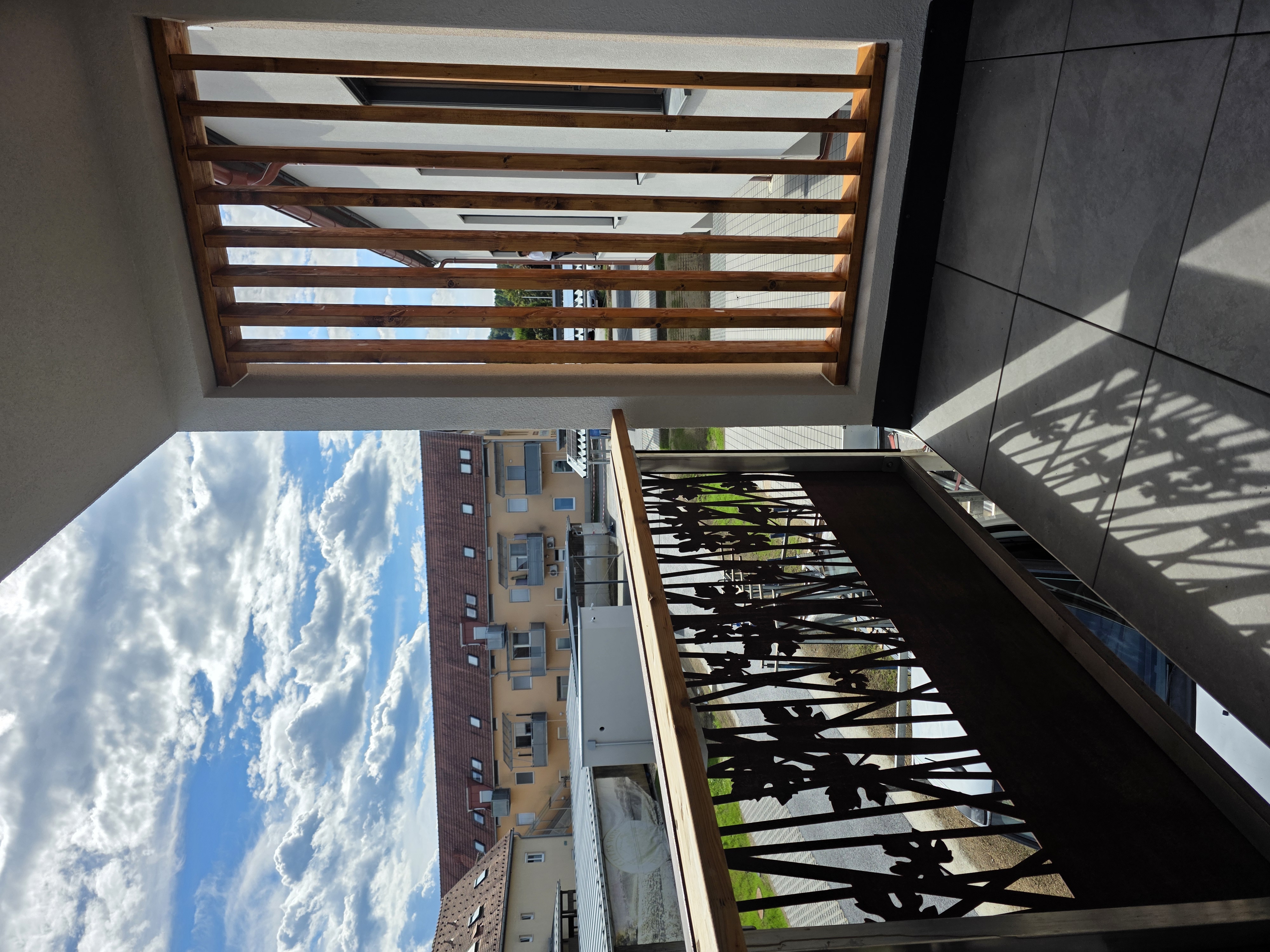 Balkon mit Corten-Geländer und Holzlamellen, Blick über den Ort