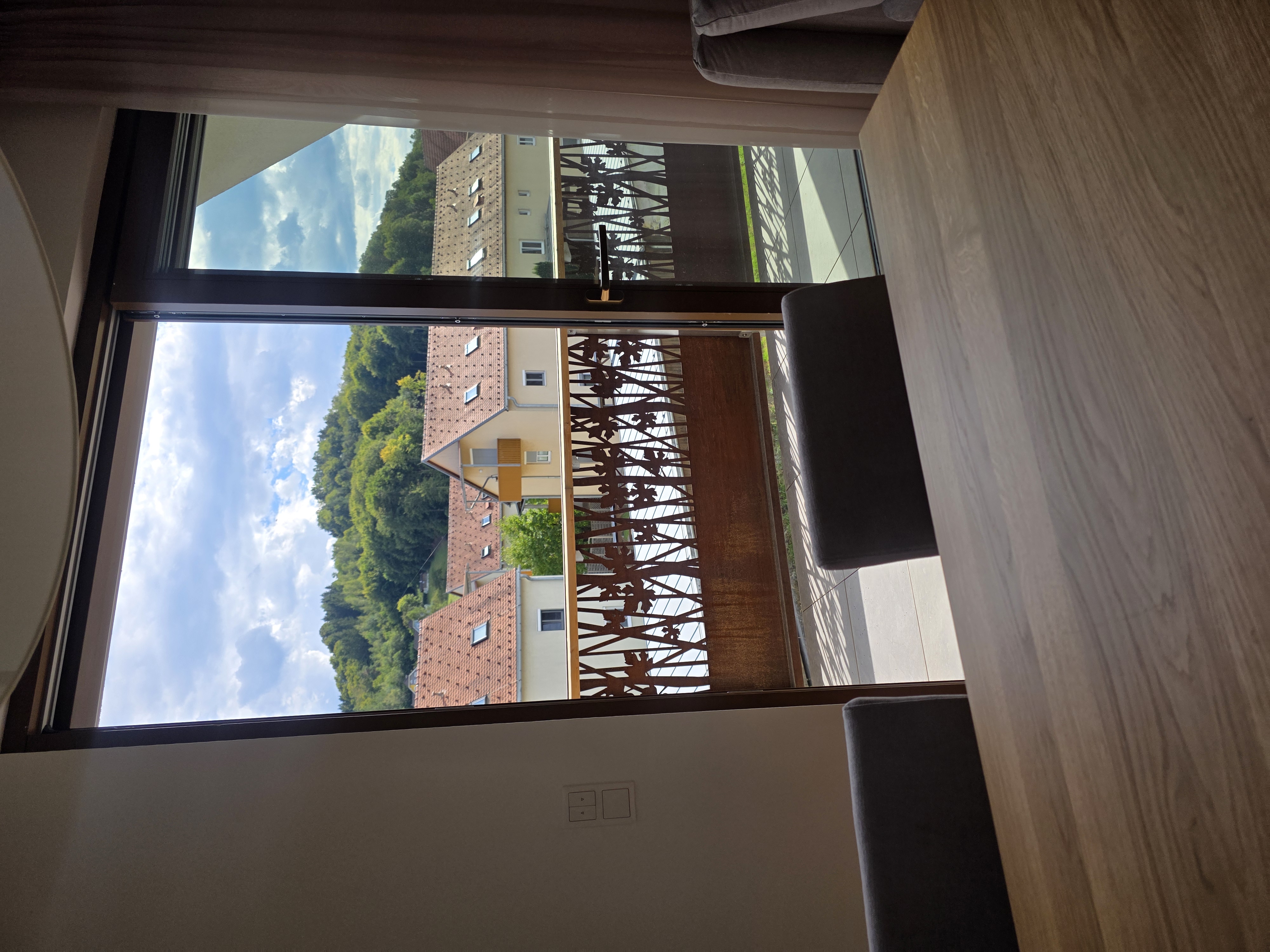 Blick vom Esstisch durch die Balkontür auf das Corten-Geländer